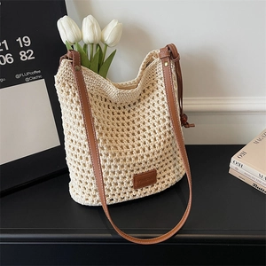 Detail of hand-woven cream tote with brown leather strap and brand label on table
