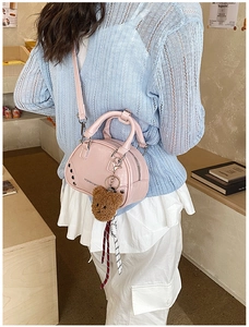 Sac Boston rose avec rivets et breloque ours porté à l'épaule par une femme