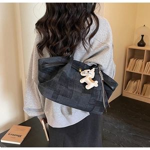 Detail of grey textured tote bag with creative horse pendant in a lifestyle setting