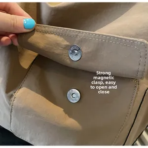 Detail of high-quality magnetic snap closure on a khaki minimalist canvas shoulder bag