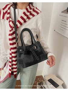 Detail of a vintage black handbag with white contrast stitching and gold buckle accents