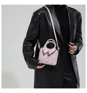 Detail of pink micro handbag with shirt-style collar and buttons on black blazer