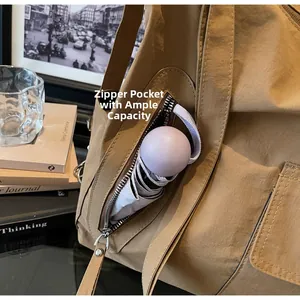 Detail view of khaki nylon tote bag featuring a side zipper pocket holding a folding umbrella