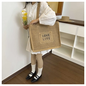 Gros plan détaillé du sac cabas en paille tressée avec broderie noire Love Life