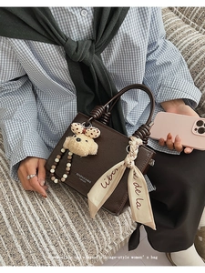 Detail of vintage dark brown faux leather handbag with silk scarf and bear charm