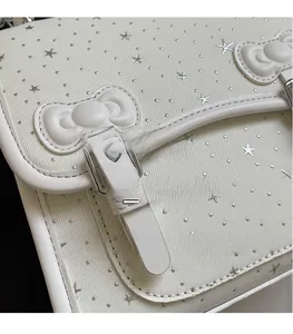Detail of white textured shoulder bag with silver star studs and a 3D decorative bow