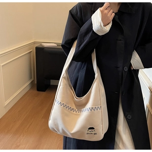 Detail of cream canvas tote bag featuring wave embroidery and cute cartoon girl portrait