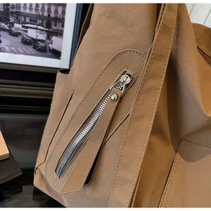 Detail view of the smooth metal zipper and reinforced stitching on a khaki brown shoulder bag