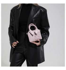 Sac à main rose en cuir en forme de chemise avec col et boutons porté par un mannequin