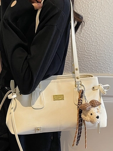 Elegant white faux leather tote bag with gold logo and cute plush bear keychain charm