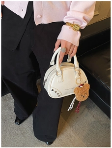 Détail du sac coquillage blanc avec rivets argentés et porte-clés ours marron