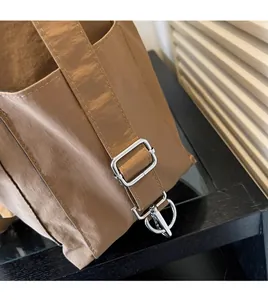 Close-up of adjustable shoulder strap and silver metal hardware on a brown nylon bag