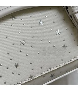Close-up of cream canvas fabric with silver star rivets and premium leather edging
