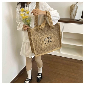 Détail du sac cabas en paille tissée avec broderie LOVE LIFE et robe vintage