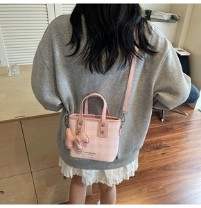 Dettaglio della mini borsa a secchiello rosa a scacchi con ciondolo a forma di cucciolo