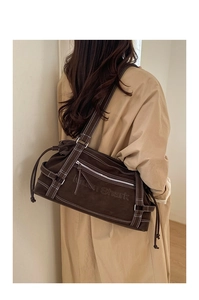 Detail of suede shoulder tote with white contrast stitching and Muen Shark embossed logo