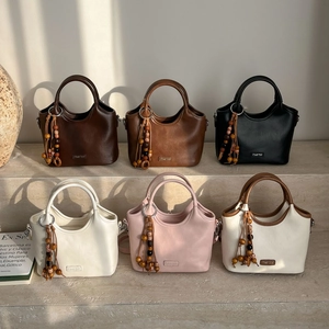 Close-up of leather bucket bags in six colors with beaded tassels and metal logo detail