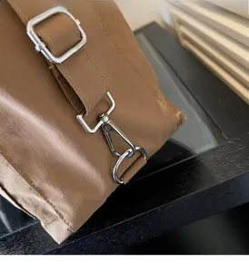 Detailed macro view of silver metal buckles and hardware on khaki shoulder bag