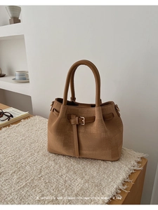 Detail of vintage tote bag featuring textured canvas, leather straps and metal buckle