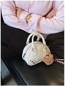 Détail du sac à main blanc avec fermeture éclair argentée et breloque ours en peluche