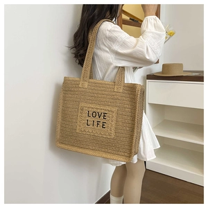 Détail du sac cabas en paille tressée avec broderie LOVE LIFE et texture naturelle