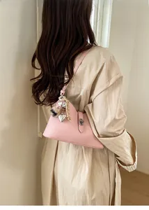 Detailed side view of pink triangle bucket bag with decorative heart and pompom charms