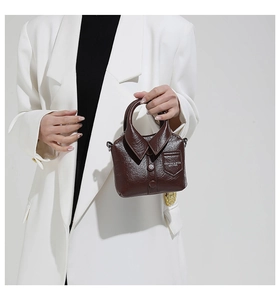 Détail d'un sac à main créatif style chemise en cuir brillant marron foncé avec bouton