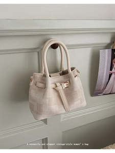 Detailed texture of a beige tweed bucket bag hanging on a vintage wall hook