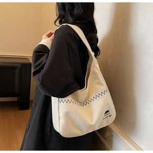 Detail of minimalist off-white canvas tote bag with blue stitching and cute girl graphic