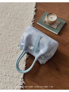 Detail view of bucket bag showing blue tie-dye texture and leather handle in cozy home setting