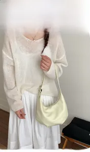 Chic cream dumpling shoulder bag with adjustable silver buckle strap on a model