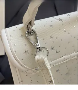 Detail of silver hardware hook and star pattern on white fabric backpack shoulder strap