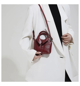 Detail of burgundy leather shirt-style mini bag with buttons and adjustable strap