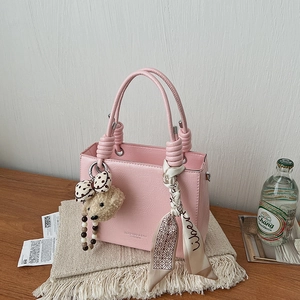 Pink lychee grain leather handbag with plush bear charm and silk scarf decoration