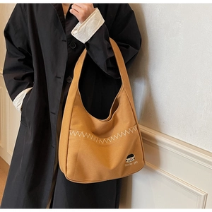 Close-up of khaki canvas tote bag with contrast stitching and decorative girl patch