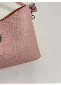 Close-up of pink lychee grain leather handbag featuring silver metal hardware and stitching