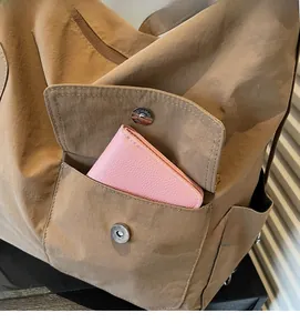 Detail of the brown nylon bag showing a magnetic flap front pocket with a pink wallet inside