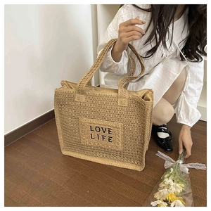 Détail de ce sac fourre-tout en paille tissée avec broderie LOVE LIFE et texture naturelle