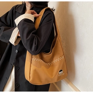 Detail of mustard yellow canvas tote bag with contrast stitching and Docile-girl embroidery