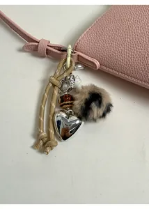 Detail of silver heart pendant and leopard print pom-pom on pink leather bag
