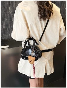Détail du sac en cuir verni noir avec rivets argentés et pendentif ours doux