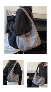 Detail view of grey canvas hobo bag with white zigzag embroidery and cute cartoon logo