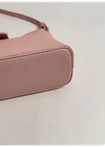 Detail view of pink lychee grain leather handbag with wide base and tonal stitching