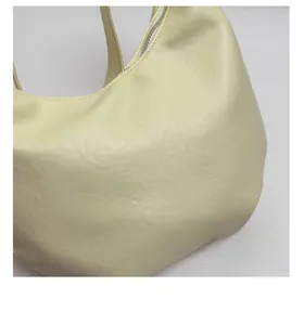 Detail shot of the creamy yellow shoulder bag showing the smooth matte leather and zipper