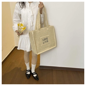 Vue détaillée du sac cabas en paille tissée avec texte LOVE LIFE et anses longues