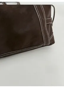 Detailed macro view of dark brown leather texture with white double contrast stitching