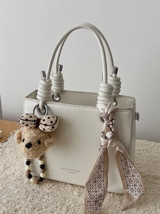 Minimalist white leather handbag with decorative teddy bear and printed silk scarf