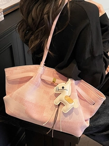 Pink checkered tote bag with horse charm on a model's shoulder for casual chic style