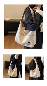 Detailed close-up of cream canvas tote bag with blue embroidery and cute cartoon pattern