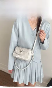 Modèle portant un sac bandoulière crème avec nœud décoratif et imprimé artistique chic